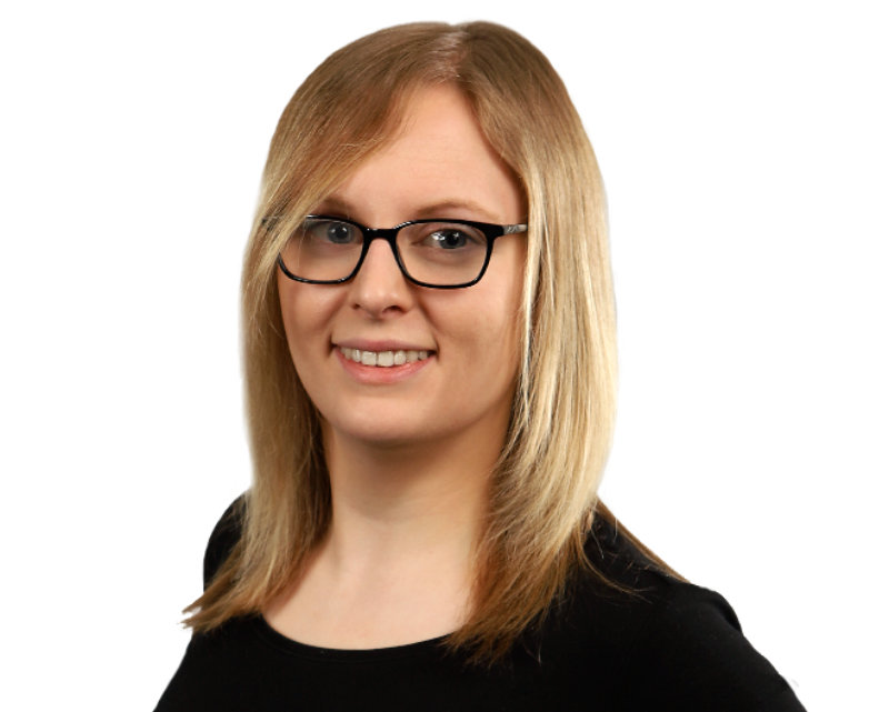 Alex Edwards has shoulder length blonde hair and black rimmed glasses. She is smiling and wears a black top.