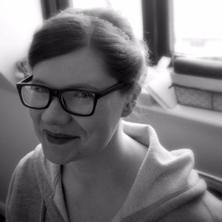 Steph Taylor-Beale is pictured in front of a window. She is wearing a hoody, has her hair tied back and is wearing black-rimmed glasses.