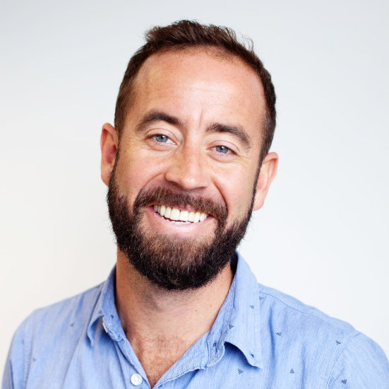 Steve Rackley is wearing a blue summer shirt, he is smiling and has a beard.